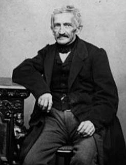 B&W photograph of Leupold von Löwenthal sitting, with his right arm resting on a table or cupboard